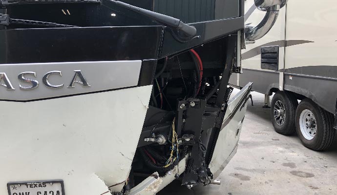 Close-up of a damaged RV front end showing broken panels and exposed wiring