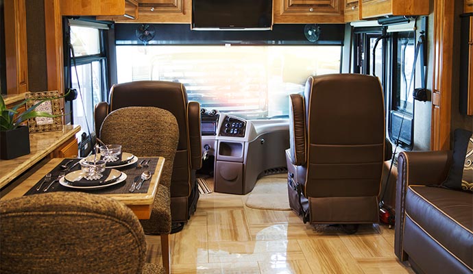 Interior of motorhome with dining table, leather seats, and driver cockpit