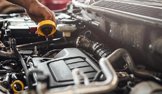 Technician checking engine fluid by holding the oil cap during RV maintenance