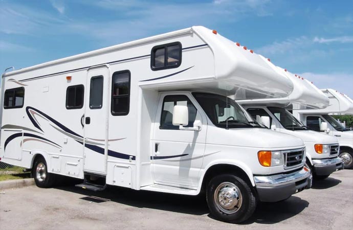 Several white RVs parked in a lot on a sunny day.