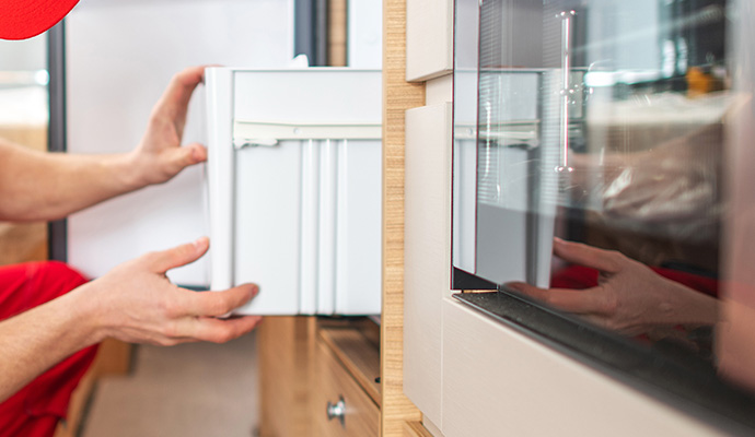 rv technician worker repairing motorhome refrigerator